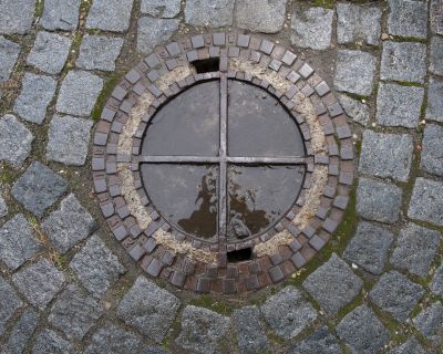 W nawierzchni na zapleczu Urzędu Pocztowego przy ul. Moniuszki 1 znajdują się także inne wyroby fabryczne Salomona Zweiga, a mianowicie  zesp&oacute;l siedmiu okrągłych właz&oacute;w o bardziej "ażurowej" formie. Fot. Bogdan Szczupaj, Pola Antonina Słomińska, Galeria Fotografii Miasta Rzeszowa